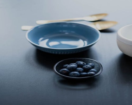 Fresh blue berries in a ceramic bowl on a wooden table